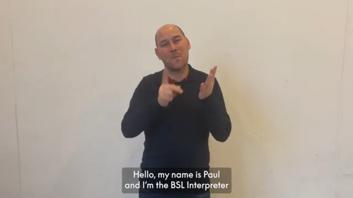 Paul, the Get Happy BSL interpreter signs against a grey background.