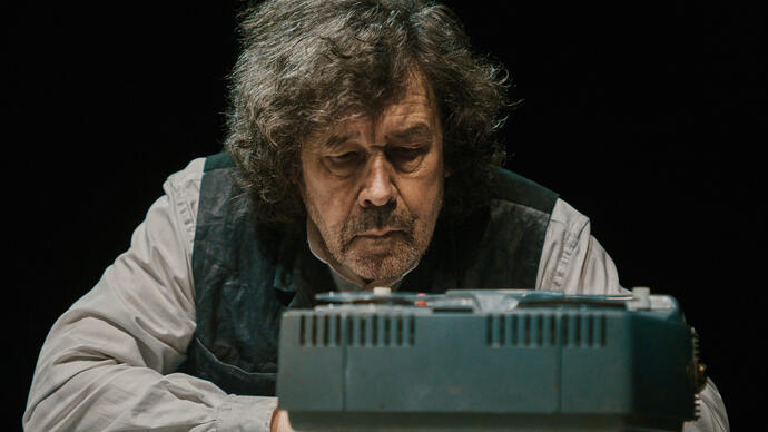 Actor Stephen Rea sits in front of a tape machine.