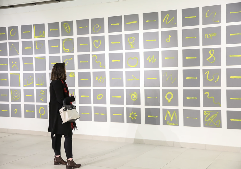 An image of a woman looking at Charles Harrison's Single Yellow Lines: exploring single and expressive gestures through paint with people with and without dementia. 2017.