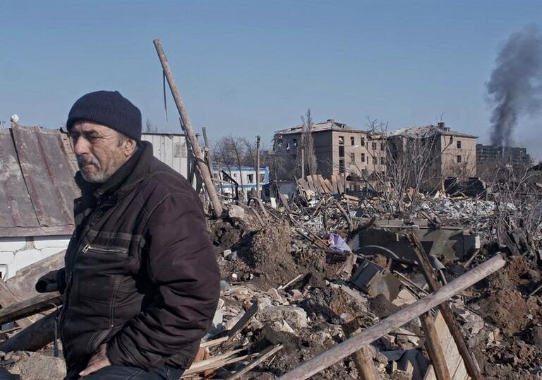 A man stands amongst the wreckage of a city