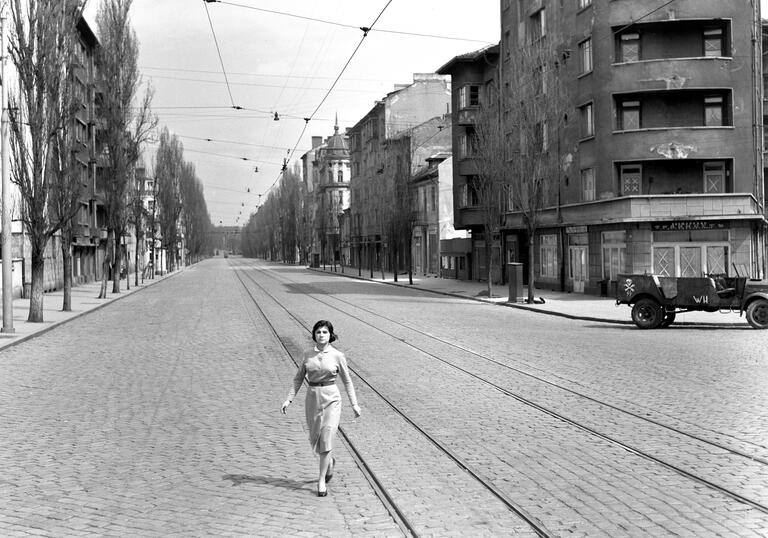 A woman stands alone in a street