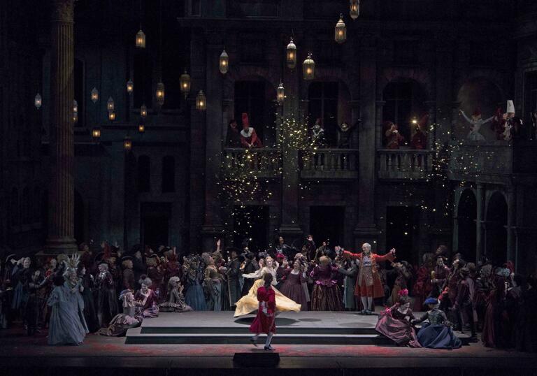 Juliette stands on a dark stage in a pool of light