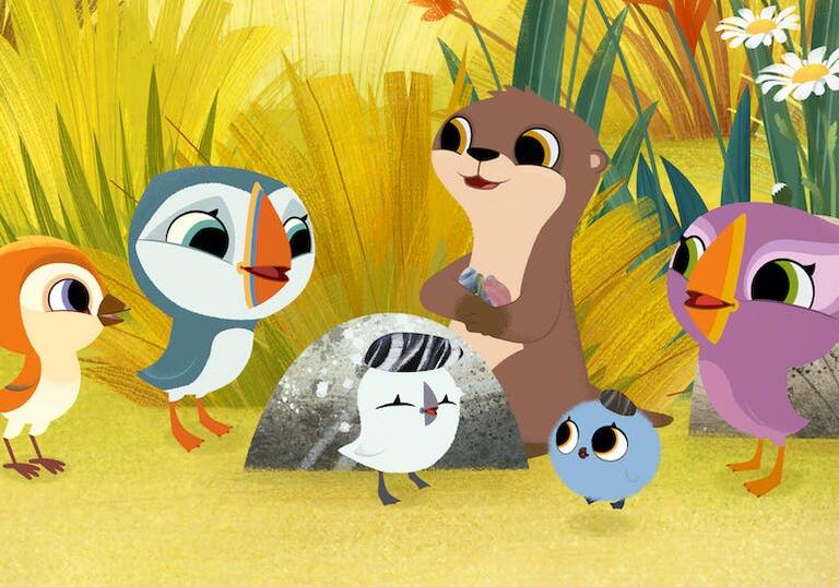 A puffin and their friends stand in a group on a beach looking happy.