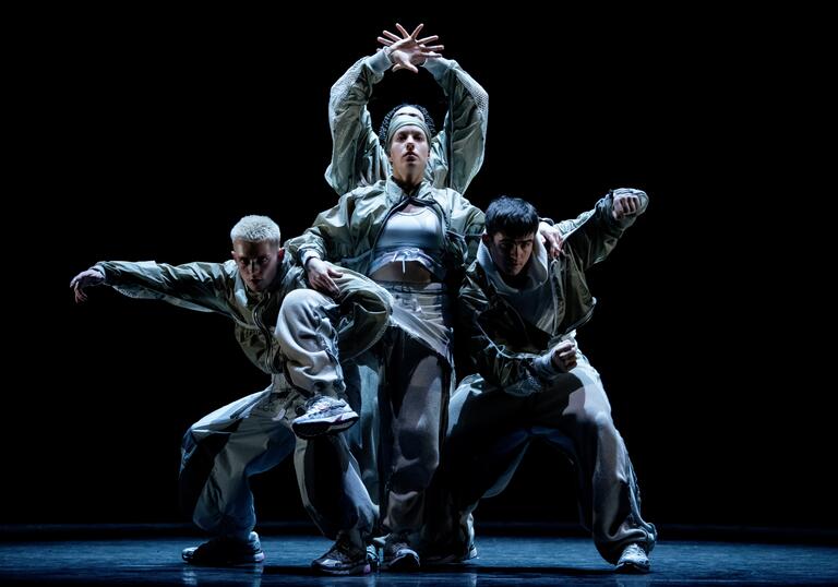A group of dancers move around each other. They move at different levels creating one moving entity.