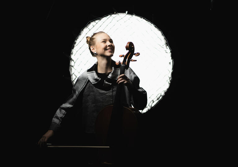 Valerie Fritz holding a cello in front of a stage light