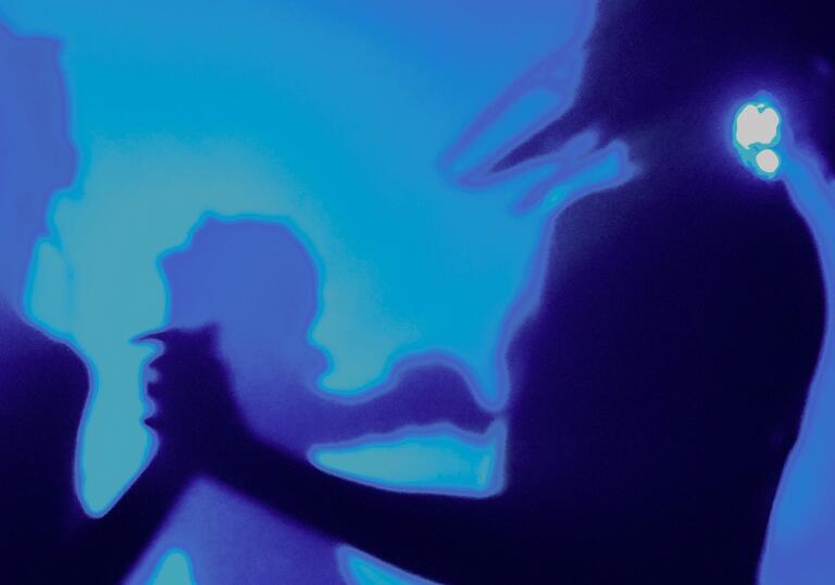 Silhouettes of people dancing in a room lit by a blue light.