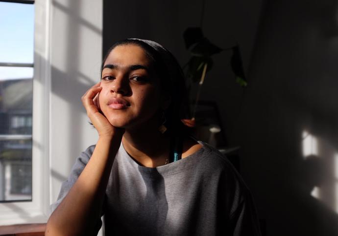 person sitting in a dark room by a window