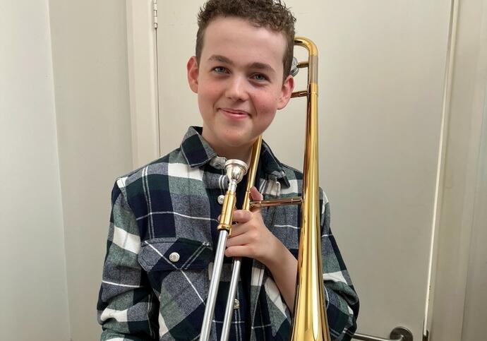 Image of Jonah, wearing checked shirt and holding trombone