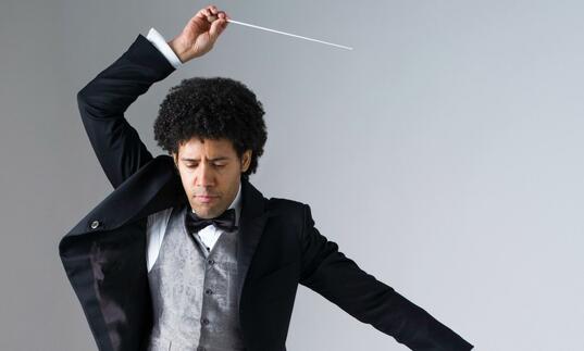 Rafael Payare striking a pose with his baton held above his head