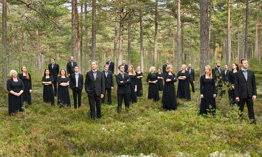 Estonian Philharmonic Chamber Choir standing in the forest