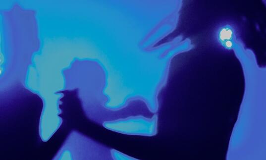 Silhouettes of people dancing in a room lit by a blue light.